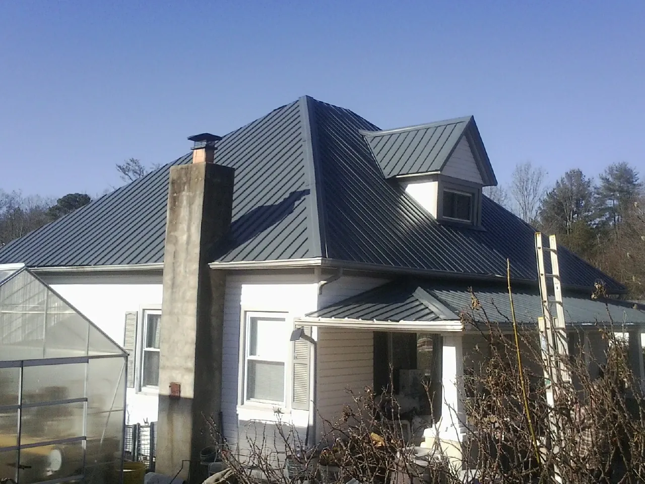Dark blue standing seam metal roof on a white farmhouse with dormer — Slate & Tile Roof Repair by Roofing Brothers in Wadena