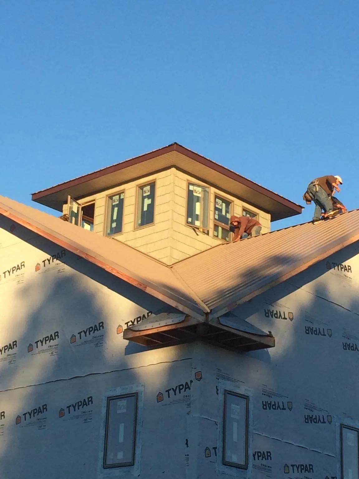 Roofers working around a rooftop cupola on a new metal roof at sunset — Roof Waterproofing in Wadena by Roofing Brothers